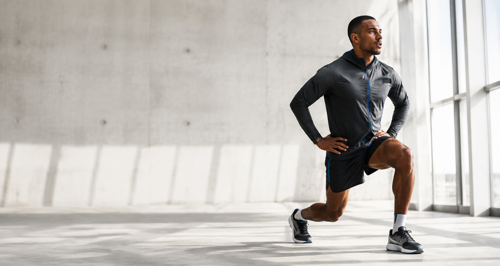 Runner wearing lightweight black and electric-blue performance clothing in a bright modern training space
